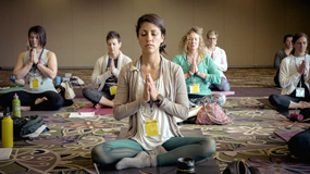 Group of females all with eyes closed in a room meditating