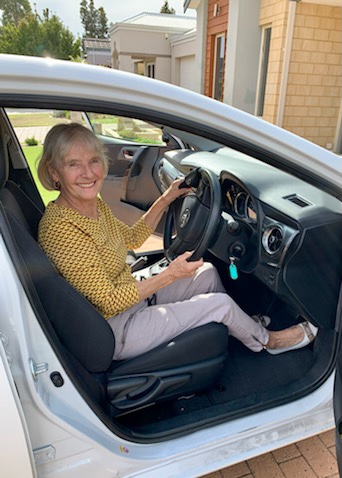 Smiling mature woman in the drivers seat of white car