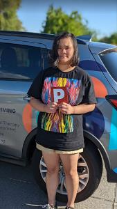Young female standing next to Indigo vehicle in shorts and patterned t-shirt holding P plate