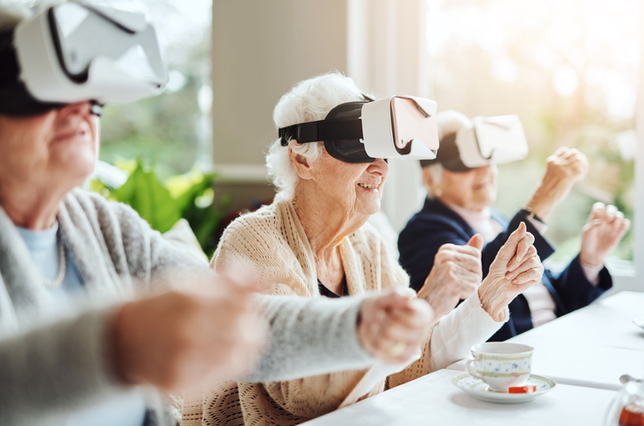 Three older persons sitting at a table using virtual reality