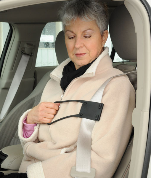 Older female in passenger seat using seat belt helper to put on her seat belt