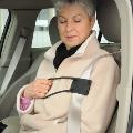 Older female in passenger seat using seat belt helper to put on her seat belt