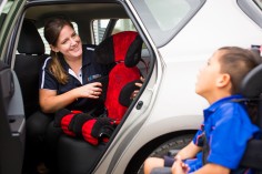 female OT in car positioning a car seat for a young boy in a powered wheelchair