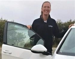 Female Indigo staff member in a polo shirt standing outside and open car door