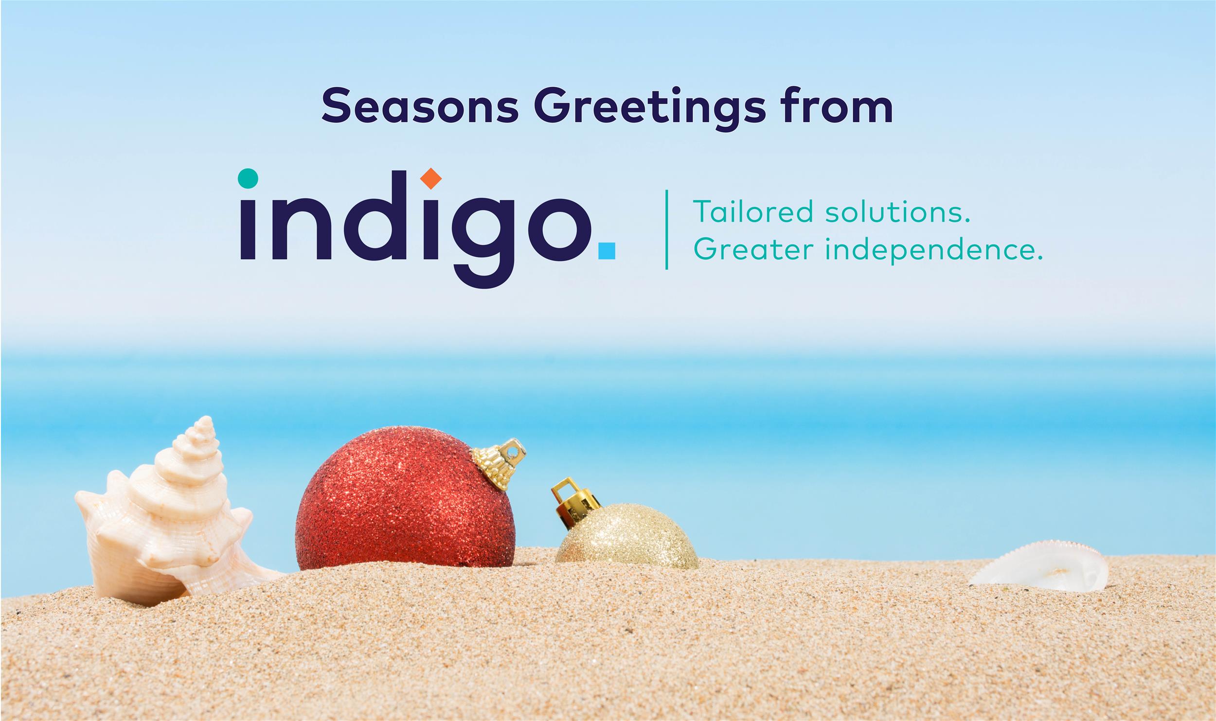 Indigo logo & text on a beach background with sand, shells and a bauble