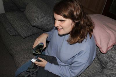 Younger female sitting on a couch using a clothes tag scanner