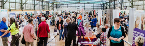 Lots stalls and people wondering about in an indoor space