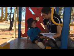 Female Indigo schools team member using AAC with a student in the playground